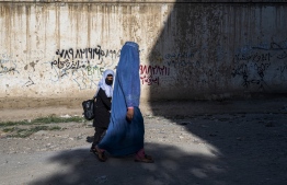 In this picture taken on August 9, 2022, an Afghan woman and a girl walk to a primary school in Kabul. - One year on from the Taliban's return to power in Afghanistan, some cracks are opening within their ranks over the crucial question of just how much reform their leaders can tolerate. Infamous during their first reign for their brutal crackdowns on rights and freedoms, the Islamists vowed to rule differently this time. -- Photo: Wakil Kohsar / AFP
