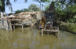 In this picture taken on August 28, 2022, Ghulam Rasool places a bedsheet on a charpai in his flood-damaged mud house on the outskirts of Sukkur, Sindh province. - The death toll from monsoon flooding in Pakistan since June has reached 1,061, according to figures released on August 29, 2022, by the country's National Disaster Management Authority. -- Photo: Asif Hassan / AFP