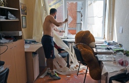 A teacher removes broken glass in a room of a public school following an air strike in Kharkiv on August 27, 2022, amid the Russian invasion of Ukraine. Russia’s invasion caused more than two million children to leave the country and displaced three million internally between February and June, according to UNICEF. -- Photo: Sergey Bobok / AFP