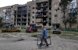 A man walks towards a damaged residential building in the town of Irpin on September 11, 2022, amid the Russian invasion of Ukraine. - Ukraine said on Sptember 11, 2022, that its forces were pushing back Russia's military from strategic holdouts in the east of the country after Moscow announced a retreat from Kyiv's sweeping counter-offensive. (Photo by SERGEI CHUZAVKOV / AFP)