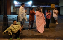 Residents stand in a street after a 6.8-magnitude earthquake in Mexico City on September 22, 2022. (Photo by Pedro PARDO / AFP)
