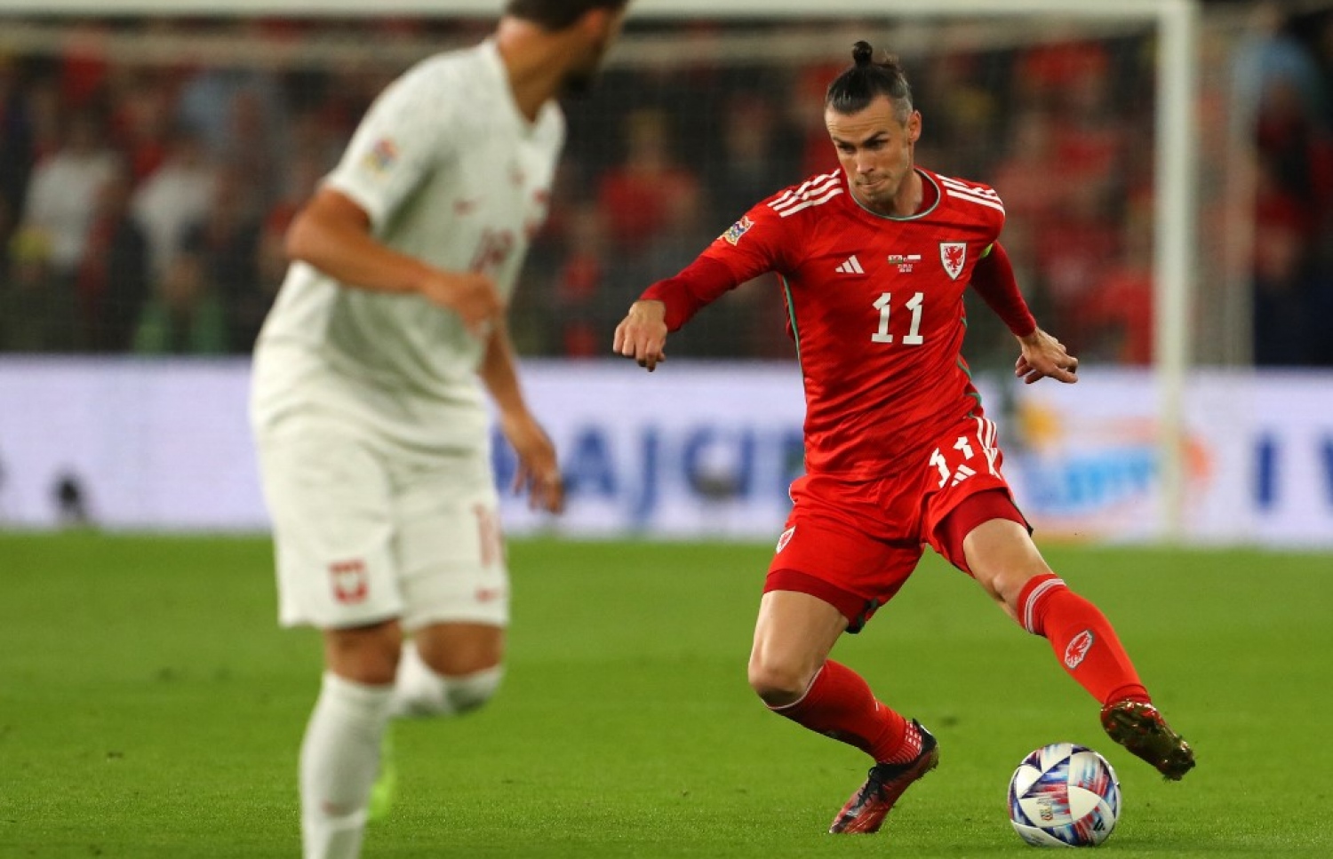 ޕޮލެންޑާ ދެކޮޅަށް ކުޅުނު މެޗުގައި ވޭލްސްގެ ކެޕްޓަން ބޭލް، ބޯޅަ ހިފައިގެން ކުރިއަށް ދަނީ. -- ފޮޓޯ: އޭއެފްޕީ