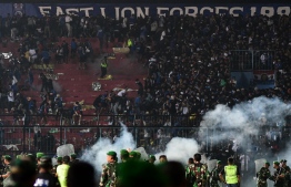 This picture taken on October 1, 2022 shows security personnel (lower) on the pitch after a football match between Arema FC and Persebaya Surabaya at Kanjuruhan stadium in Malang, East Java. - At least 125 people died at a football stadium in Indonesia late on October 1 when fans invaded the pitch and police responded with tear gas, triggering a stampede, officials said. (Photo by AFP)