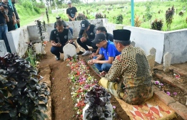 Arema FC players visit a tomb of a victim of a deadly stampede following a football match in Malang on October 3, 2022. - Anger against police mounted in Indonesia on October 3 after at least 125 people were killed in one of the deadliest disasters in the history of football, when officers fired tear gas in a packed stadium, triggering a stampede. -- Photo: Putri / AFP