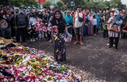 A woman grieves as she pays her respects for victims of the stampede at Kanjuruhan stadium in Malang, East Java on October 4, 2022. - Elite Indonesian police officers were under investigation on October 4 over a stadium stampede that killed 125 people including dozens of children in one of the deadliest disasters in football history. -- Photo: Juni Kriswanto / AFP