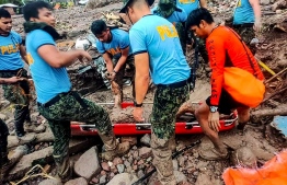 In this handout photo taken and released by the Philippine Coast Guard on October 28, 2022 rescue workers retrieve the body of a victim during a rescue and retrieval operations in Datu Odin Sinsuat, Maguindanao. - Landslides and flooding killed at least 31 people as heavy rain from an approaching storm lashed the southern Philippines, with some residents stranded on rooftops, a disaster official said on October 28. (Photo by Handout / Philippine Coast Guard (PCG) / AFP)
