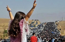 (FILE) This UGC image posted on Twitter reportedly on October 26, 2022 shows an unveiled woman standing on top of a vehicle as thousands make their way towards Aichi cemetery in Saqez, Mahsa Amini's home town in the western Iranian province of Kurdistan, to mark 40 days since her death, defying heightened security measures as part of a bloody crackdown on women-led protests.  -- Photo by UGC / AFP