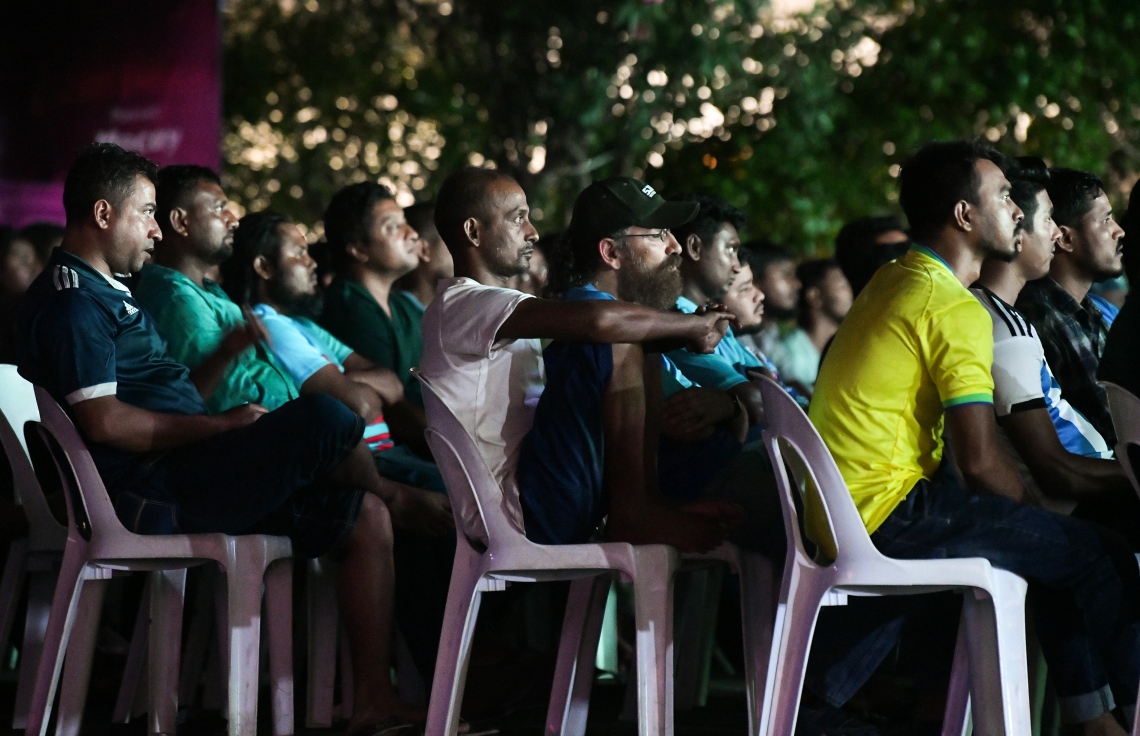 ބިދޭސީން ސޯޝަލް ސެންޓަރުގައި އިކުއެޑޯއާ-ގަތަރުގެ މެޗު ބަލަނީ: އެ ތަނުގައި ހުރި ގޮނޑިތައް ފުރިގެން ގިނަބަޔަކު ކޮޅަށް ވެސް ތިބި.--- ފޮޓޯ: ފަޔާޒު މޫސާ | މިހާރު