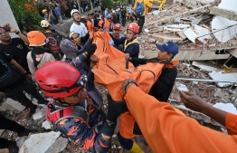 Rescue workers carry the body of a victim in Cianjur on November 22, 2022, following a 5.6-magnitude earthquake that killed at least 162 people, with hundreds injured and others missing. -- Photo: Adek Berry / AFP