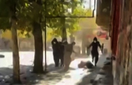This image grab from UGC video footage posted on November 21, 2022 reportedly shows what appears to be a person on the ground as Iranian protesters take cover while security forces fire live ammunition in a street in the Kurdish-majority city of Javanrud, in the western province of Kermanshah. -- Photo: UGC / AFP)
