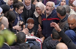 The grandparents of one of Palestinians killed during clashes with Israeli army forces mourn with others around the body during the funeral in their home village of Beit Rima in the occupied West Bank on November 29, 2022. - Israeli troops shot dead three Palestinians in the occupied West Bank on November 29, Palestinian officials said, before a suspected car-ramming attacker was killed after seriously wounding an Israeli soldier, Israeli medics and the army said. The army confirmed its troops had fired on "rioters" who attacked soldiers in two separate West Bank clashes overnight. -- Photo: Jaafar Ashtiyeh / AFP