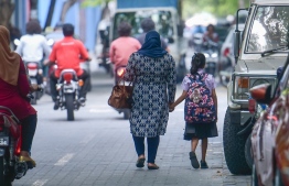 A woman and child walking on the streets of Male' City.