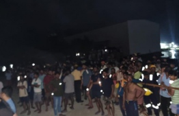 Afcons staff living in the accommodation  block located in Gulhifalhu  gathered outside  as firefighters try to extinguish the fire: The accommodation block housed 465 people. -- Photo: MNDF