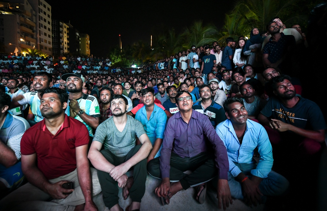 ފްރާންސާއި އާޖެންޓީނާ ކުޅުނު މި އަހަރުގެ ވޯލްޑްކަޕް ފައިނަލް މެޗު ބަލަން މާލޭގެ އާޓިފިޝަލް ބީޗަށް މީހުން ޖަމާވެފައި: މީގެ ތެރޭގައި ގިނައީ ބަންގްލަދޭޝްގެ ސަޕޯޓަރުން.--- ފޮޓޯ: ފަޔާޒު މޫސާ | މިހާރު