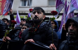 Protesters hold roses while taking part in a demonstration to pay tribute to the Enghien Street shooting victims in Paris on December 23, 2022, and to those of La Fayette street murders in 2013, as they march in solidarity with the Kurdish community in Paris on December 26, 2022. - A 69-year-old French man suspected of killing three Kurds and injuring three others in a Paris shooting has confessed to a "pathological" hatred for foreigners, Paris prosecutor Laure Beccuau said on December 25, 2022. The suspect spent nearly a day in a psychiatric facility on December 25, before being returned to police custody on the same day. -- Photo: Julien De Rosa / AFP