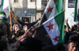 Demonstrators raise Syrian opposition flags and placards as they rally against a potential rapprochement between Ankara and the Syrian regime, on December 30, 2022, in the opposition-held city of al-Bab, on the border with Turkey, in Syria's northern Aleppo province. -- Photo by Bakr Alkasem
/ AFP