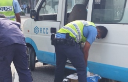 Screenshot of a video showing officers of Maldives Police Service confiscating alcoholic beverages from a van with RCC Construction's logo--