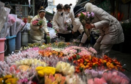 People buy flowers in a flower market in Wuhan, in China's central Hubei province on January 21, 2023, ahead of the start of the Lunar New Year, which ushers in the Year of the Rabbit on January 22. (Photo by Hector Retamal / AFP