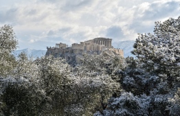The Acropolis archaeological site is seen after a snowfall in Athens on February 6, 2023. (Photo by Louisa Gouliamaki / AFP
