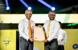 MDP Chairperson Fayyaz Ismail handing over the party's presidential ticket to President Ibrahim Mohamed Solih at a rally held in the Carnival area in Malé on 17th February 2023. PHOTO: NISHAN ALI / MIHAARU