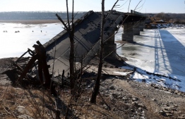 Local residents fish near a destroyed bridge at the frozen Oskil reservoir near the town of Borova, in the Kharkiv region on February 23, 2023, amid the Russian invasion of Ukraine. (Photo by Anatolii Stepanov / AFP)