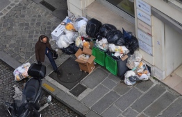 A man walks past piles of garbage up along a street in Paris on March 14, 2023, since collectors went on strike against the French government's proposed pensions reform. - Thousands of tonnes of garbage have piled up on streets across the French capital after a week of strike action by dustbin collectors against government pension reforms, city hall said on March 12, 2023. -- Photo: Zakaria Abdelkafi / AFP