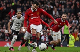 Manchester United's Portuguese midfielder Bruno Fernandes scores their first goal from the penalty spot during the English FA Cup quarter-final football match between Manchester United and Fulham at Old Trafford in Manchester, north-west England, on March 19, 2023. -- Photo by Paul Ellis / AFP