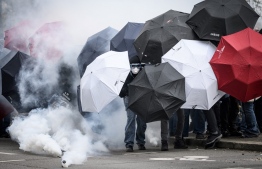 Protestors protect themselves from tear gas smoke with umbrellas during the 11th day of action after the government pushed a pensions reform through parliament without a vote, using the article 49.3 of the constitution, in Nantes, western France, on April 6, 2023. France on April 6, 2023 braced for another day of protests and strikes to denounce French President's pension reform one day after talks between the government and unions ended in deadlock. -- Photo: Loic Venance / AFP