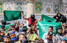Men hold up banners showing the Islamic Shahada (the creed stating a belief in one god and the acceptance that Mohammed was God's prophet), outside the Dome of the Rock shrine at al-Aqsa mosque compound in the Old City of Jerusalem on April 7, 2023 on the third Friday Noon prayer during the Muslim holy fasting month of Ramadan. -- Photo: Ahmad Gharabli / AFP