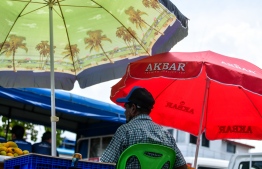 A person taking shade under an umbrella during the hot weather