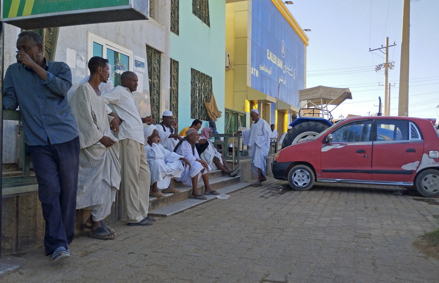 މެއި 1، 2023؛ ސޫދާންގެ ދާޚިލީ ހަނގުރާމައިގެ ސަބަބުން ވެރިރަށް ޚަރްތޫމްގެ ވިޔަފާރިތައް ބަންދުކޮށްފައިވާ އިރު، އާންމުންގެ ބަޔަކު ބޭންކު ހުޅުވާނެ ކަމުގެ އިންތިޒާރުގައި ބޭންކުގެ ބޭރުގައި ކިޔޫ ހަދައިގެން. --އޭއެފްޕީ