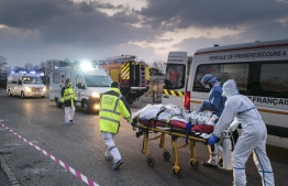 In this file photograph taken on March 29, 2020, emergency medical personnel carries a patient affected with coronavirus (Covid-19) from a military hospital to an ambulance before being transported aboard a medicalised TGV (high-speed train) to be evacuated towards hospitals of other French regions, in Mulhouse, eastern France, amid the spread of the COVID-19 (new coronavirus) pandemic. -- Photo: Sebastien Bozon / AFP
