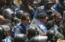 Policemen escort Pakistan's former Prime Minister Imran Khan (C) as he arrives at the high court in Islamabad on May 12, 2023. Khan appeared at court for a bail hearing on May 12, after the Supreme Court ruled unlawful his arrest this week that triggered deadly clashes across the country. -- Photo: Aamir Qureshi / AFP