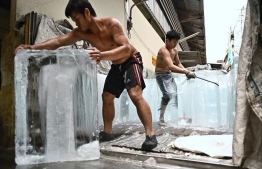 (FILES) In this file photo taken on April 25, 2023, workers move blocks of ice into a storage unit at a fresh market during heatwave conditions in Bangkok. Climate change made record-breaking deadly heatwaves in Bangladesh, India, Laos and Thailand last month at least 30 times more likely, according to a study published on May 17. --Photo: Lillian Suwanrumpha / AFP