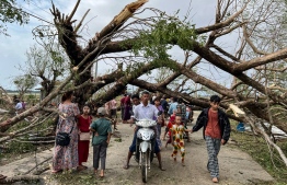 (FILES) Residents walk past fallen trees in Kyauktaw in Myanmar's Rakhine state on May 15, 2023, after Cyclone Mocha crashed ashore. The death toll from Cyclone Mocha that barrelled through Myanmar has reached 145 in the country, the junta's information team said in a statement on May 19. -- Photo: Sai Aung Main / AFP