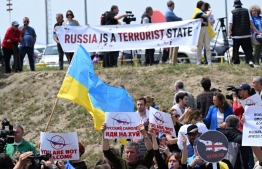 A picture taken on May 19, 2023 shows demonstrators protesting against the resumption of air links with Russia outside the Tbilisi Airport as the Azimuth Airline passenger plane, conducting the first direct flight from Moscow, arrives in Tbilisi. Last week, Russian President Vladimir Putin lifted a flight ban with Georgia, against which Russia fought a brief war in 2008. Putin has also introduced a 90-day visa-free regime for Georgian citizens, after Russia in 2019 banned air travel with the country in response to anti-Moscow rallies in Georgia. -- Photo: Vano Shlamov / AFP