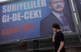 A pedestrian walks past a campaign billboard of Republican People's Party (CHP) presidential candidate Kemal Kilicdaroglu, reading "Syrians will go," and asking the voters to "decide", in Resatbey neighbourhood, central Adana, on May 25, 2023. Secular candidate Kemal Kilicdaroglu alarmed his leftist Kurdish supporters by starting to court staunchly nationalist voters after losing to the incumbent president in the first round on May 14. He has pledged to send "all the refugees home" if he wins in a presidential runoff election on May 28, 2023. -- Photo: Can Erok / AFP