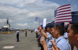 Philippine coast guard personnel (R) wave US flags as US coast guard ship Stratton (L) arrives at the international port in Manila on June 1, 2023, ahead of a joint maritime exercise with the Philippines and Japan. -- Photo: Ted Aljibe / AFP