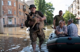 Ukrainian servicemen help local residents during an evacuation from a flooded area in Kherson on June 7, 2023, following damages sustained at Kakhovka hydroelectric power plant dam. Ukraine was evacuating thousands of people on June 7 after an attack on a major Russian-held dam unleashed a torrent of water, inundating two dozen villages and sparking fears of a humanitarian disaster. --  Photo: Aleksey Filippov / AFP