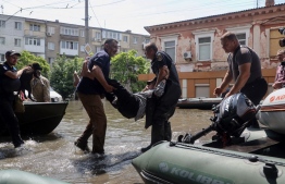 Ukrainian security forces carry an elderly resident to a boat during an evacuation from a flooded area in Kherson on June 7, 2023, following damages sustained at Kakhovka hydroelectric power plant dam. Ukraine was evacuating thousands of people on June 7 after an attack on a major Russian-held dam on June 6, 2023, unleashed a torrent of water, inundating two dozen villages and sparking fears of a humanitarian disaster. -- Photo: Oleksandr Gimanov / AFP