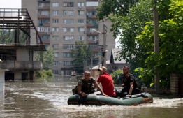 Ukrainian security forces carry on a boat a local resident during an evacuation from a flooded area in Kherson on June 7, 2023, following damages sustained at Kakhovka hydroelectric power plant dam. Ukraine was evacuating thousands of people on June 7 after an attack on a major Russian-held dam unleashed a torrent of water, inundating two dozen villages and sparking fears of a humanitarian disaster. -- Photo: Aleksey Filippov / AFP