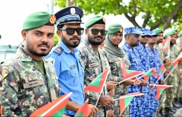 (FILE) Police and MNDF employees holding Maldives' national flag on July 2, 2023: the new pay structure for the police and MNDF employees were sent to their organisations on the last day of President Ibrahim Mohamed Solih's presidential term -- Photo: Nishan Ali / Mihaaru