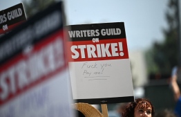 (FILES) A supporter holds sign on the Hollywood writers picket line outside Universal Studios Hollywood in Los Angeles, California, June 30, 2023. -- Photo by Robyn Beck / AFP