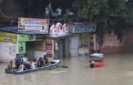 People row a boat past a flooded street after Yamuna River overflowed due to monsoon rains in New Delhi on July 14, 2023. Days of relentless monsoon rains have killed at least 66 people in India, government officials said on July 12, with dozens of foreign tourists stranded in the Himalayas after floods severed road connections. -- Photo: Arun Sankar / AFP