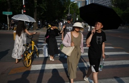People shelter under umbrellas during heatwave conditions in Beijing on July 19, 2023. --Photo: Greg Baker / AFP