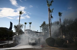 A Phoenix Fire Department firefighter uses a hose line to extinguish a Ford F150 pickup truck that caught fire during a record heat wave in Phoenix, Arizona on July 18, 2023. Swaths of the United States home to more than 80 million people were under heat warnings or advisories, as relentless, record-breaking temperatures continued to bake western and southern states. In Arizona, state capital Phoenix recorded its 17th straight day above 109 degrees Fahrenheit (43 degrees Celsius), as temperatures hit 113F Sunday afternoon. -- Photo: Patrick T. Fallon / AFP
