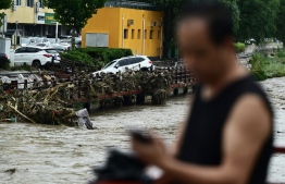 A man stands by the overflooded Yongding river, after heavy rains in Mentougou district in Beijing on July 31, 2023. Heavy rains battered northern China on July 31, killing at least two people in Beijing while washing away cars and inundating subway stations, with the capital issuing its highest alerts for flooding and landslides. -- Photo: Pedro Pardo / AFP
