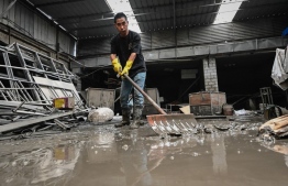 A worker clears mud from a warehouse in the aftermath of flooding from heavy rains in Zhuozhou city, in northern China’s Hebei province on August 9, 2023. China's capital has been hit by record downpours in recent weeks, damaging infrastructure and deluging swaths of the city's suburbs and surrounding areas. In Hebei province, which neighbours Beijing, 15 were reported to have died and 22 were missing. -- Photo:  Jade Gao / AFP