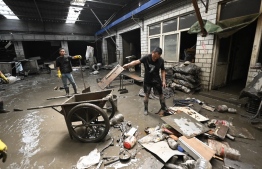 Workers clear mud and debris from a warehouse in the aftermath of flooding from heavy rains in Zhuozhou city, in northern China’s Hebei province on August 9, 2023. China's capital has been hit by record downpours in recent weeks, damaging infrastructure and deluging swaths of the city's suburbs and surrounding areas. In Hebei province, which neighbours Beijing, 15 were reported to have died and 22 were missing. -- Photo: Jade Gao / AFP