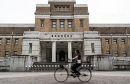 A woman rides her bicycle past the National Museum of Nature and Science at Ueno Park in Tokyo on August 9, 2023. Japan's second-oldest museum has raised 3.4 million USD through crowdfunding after reportedly being denied additional financial support to cover soaring utility bills to preserve its collection of animal and plant specimens. -- Photo: Richard A. Brooks / AFP